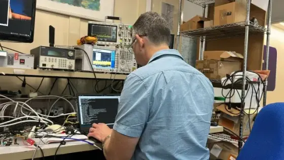 Engineer testing electronics at a lab bench with oscilloscope and signal analyzer