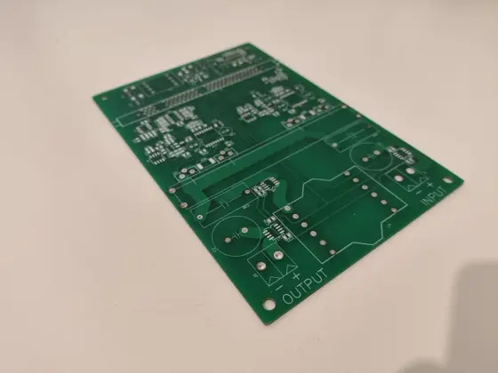 Bare custom-designed PCB board with input/output labels on lab workbench
