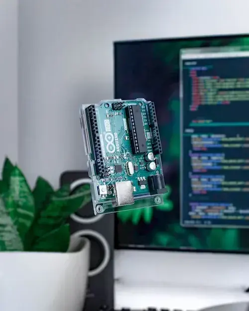 Small embedded development board connected to a monitor showing source code