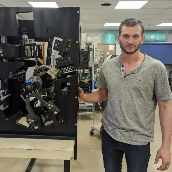 Founder standing beside a custom-built robotic assembly machine in the inteRFace R&D lab